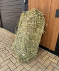 Small bale of Portuguese ryegrass hay standing upright at a stable door