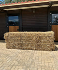 Big bale of Portuguese straw seen head-on in front of the stables